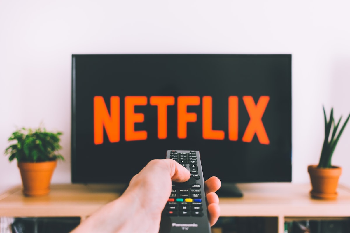 Une personne pointe une télécommande vers un téléviseur connecté pour choisir son abonnement IP TV